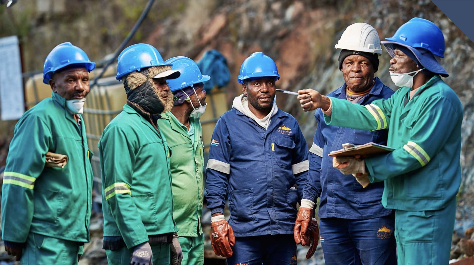 Mine workers in safety helmets and protective gear consulting on site