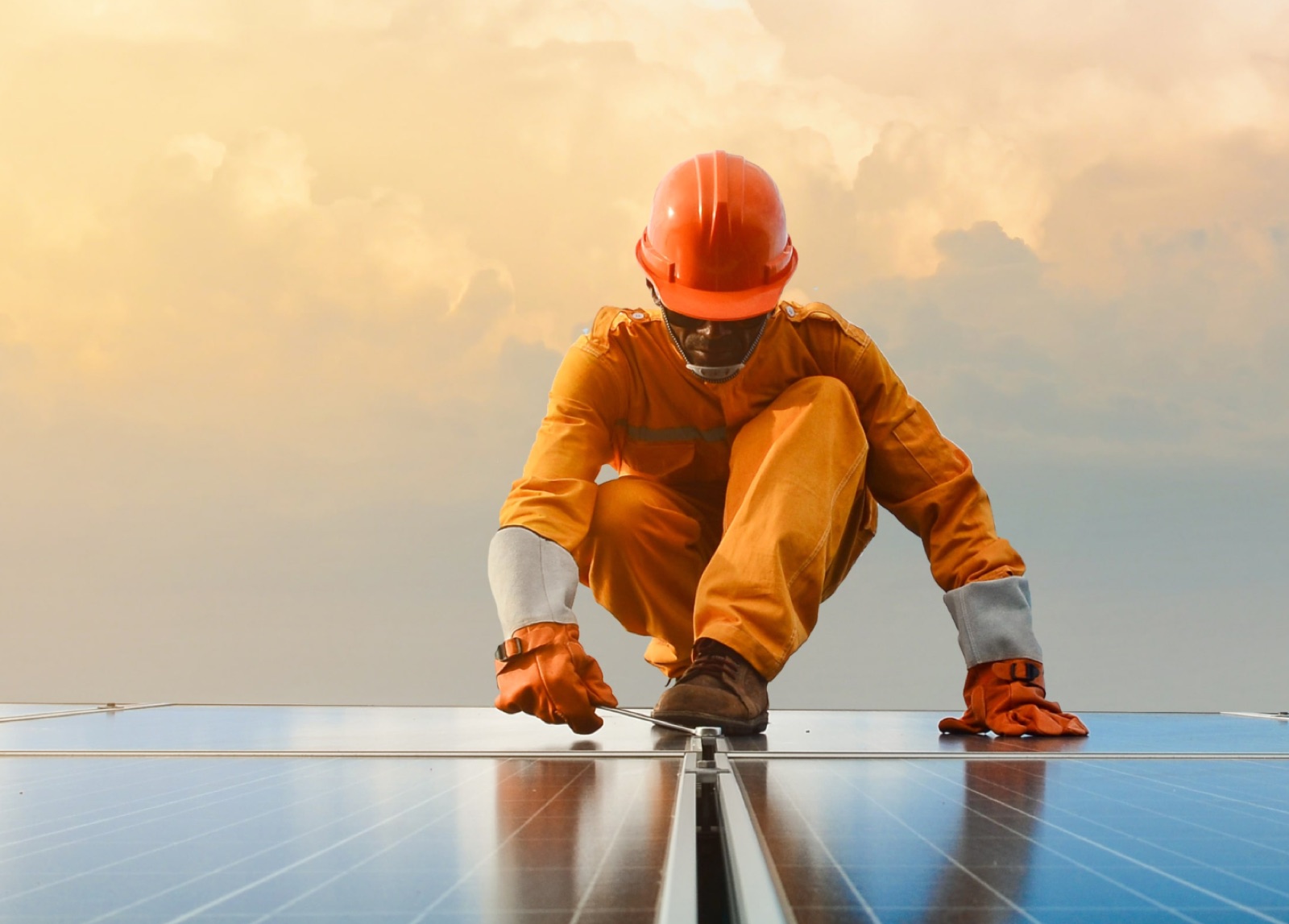 Technician installing rooftop solar panels at sunrise